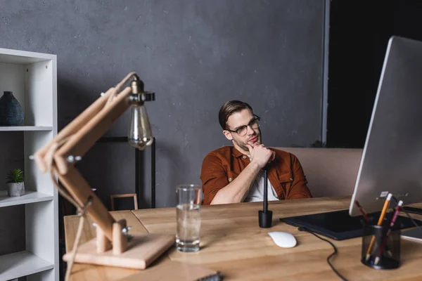 Nachdenkliche junge Designerin blickt auf Computerbildschirm — Stockfoto