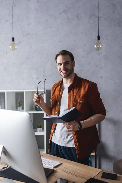 Joven hombre de negocios guapo con libro en la oficina moderna - foto de stock