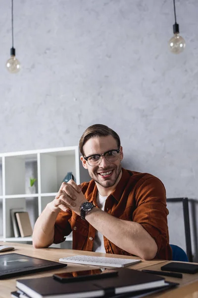 Happy young designer sitting at workplace in modern office — Stock Photo