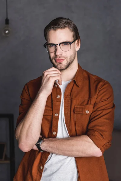 Close-up portrait of thoughtful young man in eyeglasses looking at camera — Stock Photo