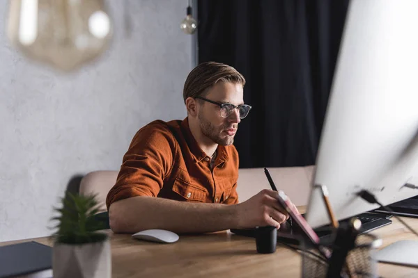 Elegante joven diseñador que trabaja con la tableta de dibujo en el lugar de trabajo - foto de stock