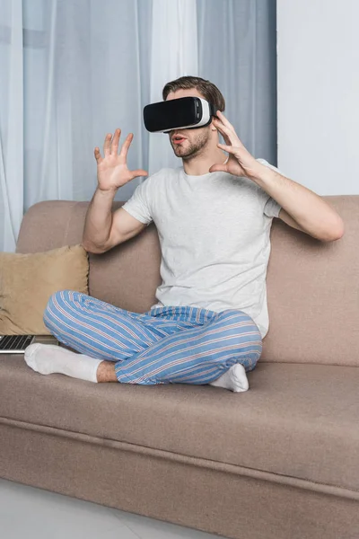 Young man in pajamas and virtual reality headset at home — Stock Photo