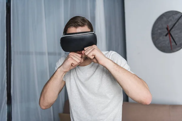 Young man in virtual reality headset playing fighting game — Stock Photo