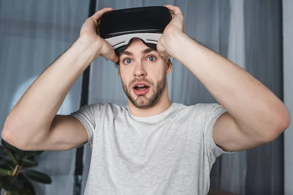 Шокований молодий чоловік у гарнітурі віртуальної реальності — стокове фото