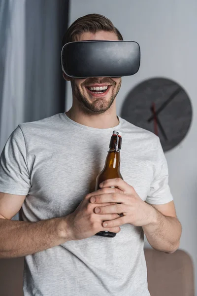 Young happy man with bottle of beer in virtual reality headset — Stock Photo