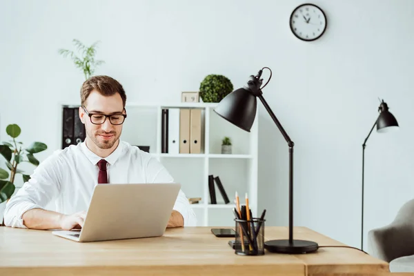 Homem de negócios bonito usando laptop no espaço de trabalho no escritório moderno — Fotografia de Stock