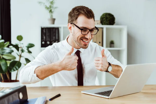 Handsome successful businessman making video call on laptop and showing thumbs up — Stock Photo