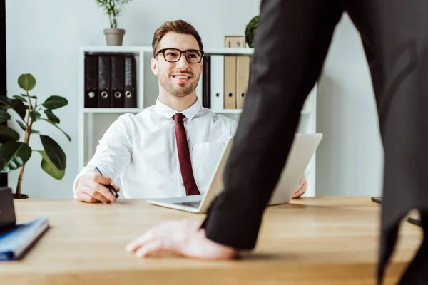 Hombre de negocios sonriente hablando con el jefe en la oficina - foto de stock