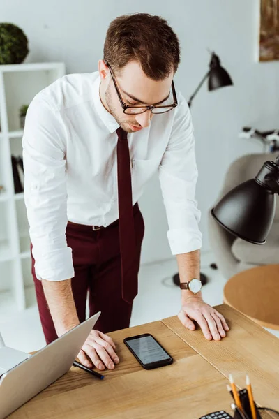 Homem de negócios elegante olhando para smartphone e esperando por chamada no local de trabalho — Fotografia de Stock