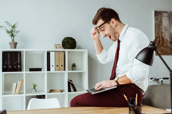 Empresário animado usando laptop no escritório moderno — Fotografia de Stock