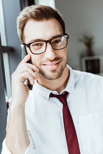 Красивый бизнесмен разговаривает на смартфоне в офисе — стоковое фото