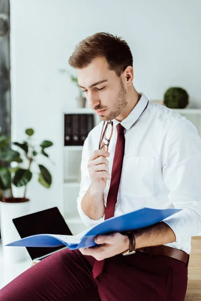 Pensativo hombre de negocios leyendo documentos de la carpeta - foto de stock