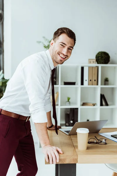 Zufriedener Geschäftsmann mit Laptop und Coffee to go am Arbeitsplatz — Stockfoto