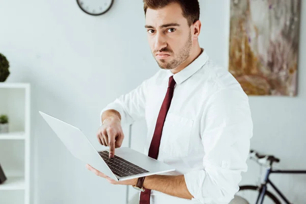 Сердитий бізнесмен в краватці використовує ноутбук в офісі — стокове фото