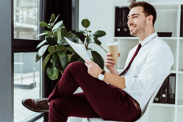 Sonriente empresario con diario de lectura de café en la oficina moderna - foto de stock