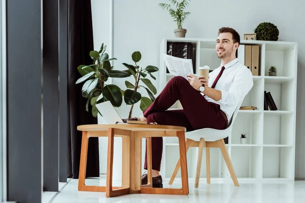 Homme d'affaires élégant avec journal de lecture de café dans le bureau moderne avec ordinateur portable — Photo de stock