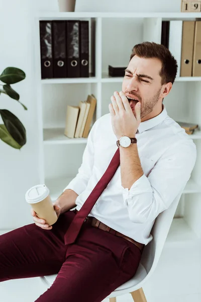 Müder Geschäftsmann mit gähnendem Kaffee im modernen Büro — Stockfoto