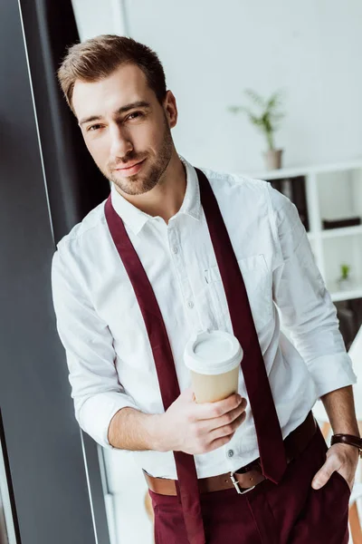 Guapo hombre de negocios con taza de café desechable en la oficina - foto de stock