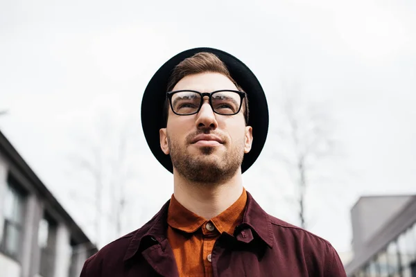 Blick von unten auf einen gut aussehenden, modischen Mann mit Brille und Hut — Stockfoto