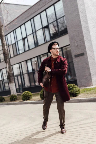 Jeune homme pressé dans des vêtements à la mode avec sac courir sur la rue — Photo de stock