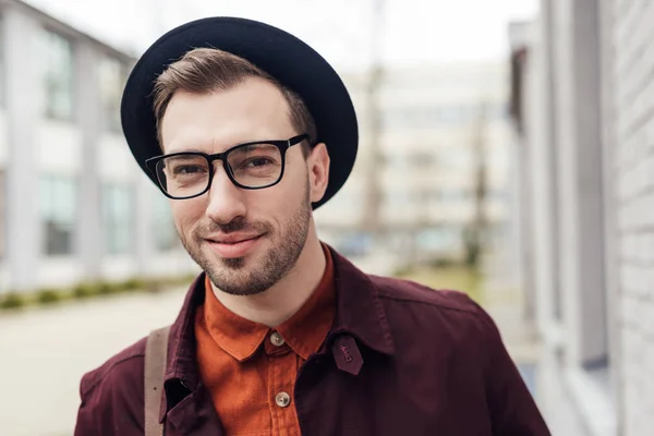 Bonito sorrindo jovem homem na moda chapéu e óculos — Fotografia de Stock