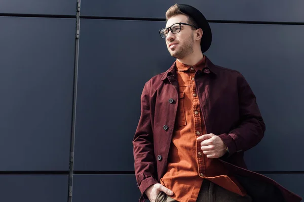 Guapo elegante hombre de pie en negro pared - foto de stock