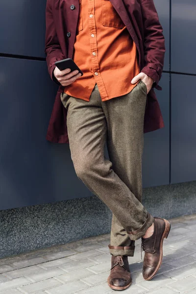 Vista de sección baja del hombre en ropa de moda utilizando el teléfono celular - foto de stock