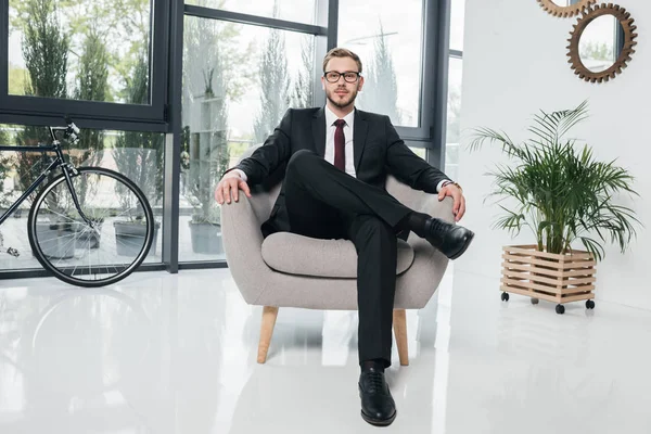 Επιχειρηματίας στο κοστούμι που κάθεται στην πολυθρόνα στο γραφείο — Φωτογραφία Αρχείου