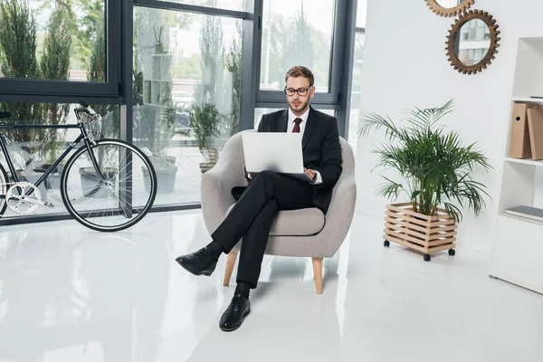 Бизнесмен работает на ноутбуке, сидя в офисе — стоковое фото