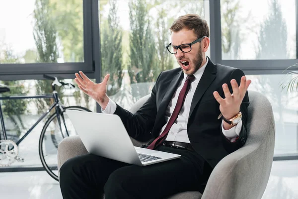 Сердитый бизнесмен кричит во время работы на ноутбуке — стоковое фото