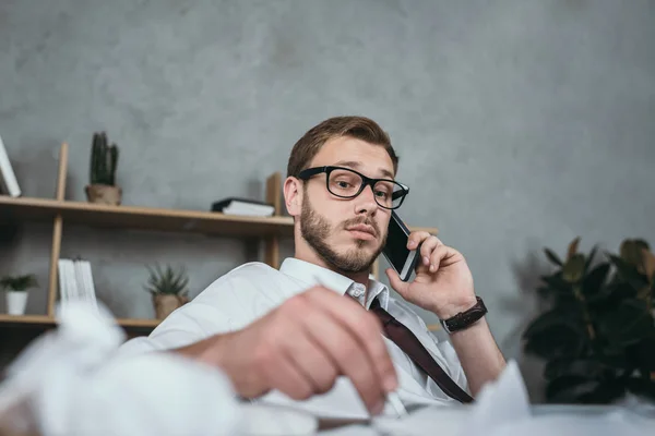 Zakenman aan het praten op smartphone terwijl hij op de werkplek zit — Stockfoto
