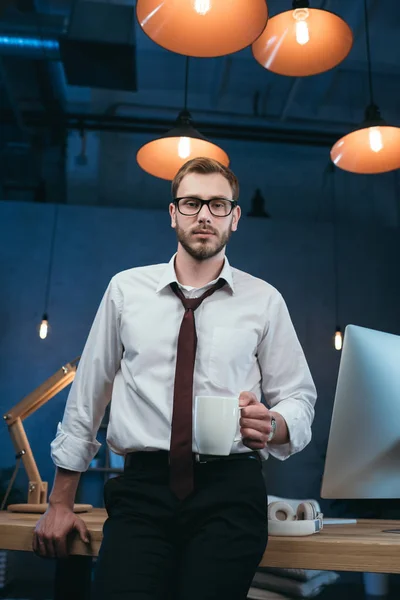Liikemies, jolla kahvikuppi toimistossa — kuvapankkivalokuva