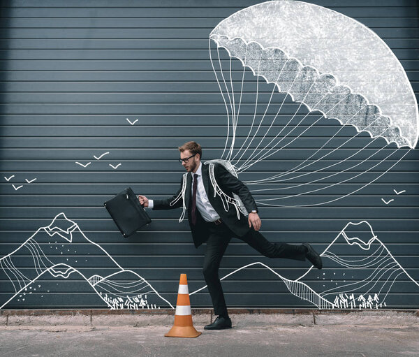 Businessman running with parachute