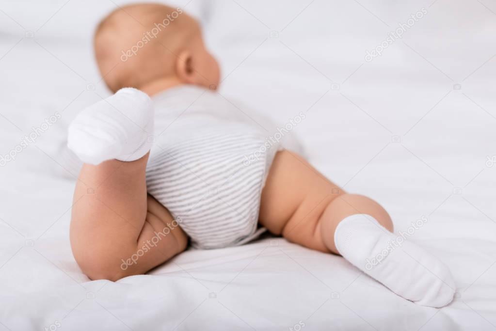 infant lying on bed