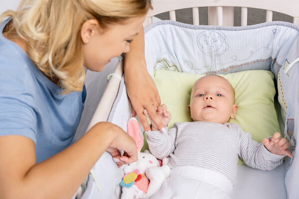 mother looking at baby in crib