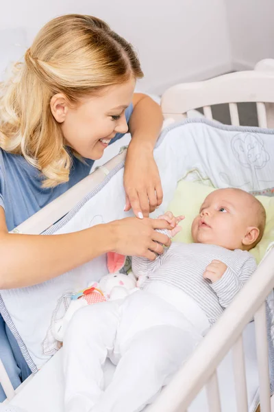 Mother looking at baby in crib — Stock Photo, Image