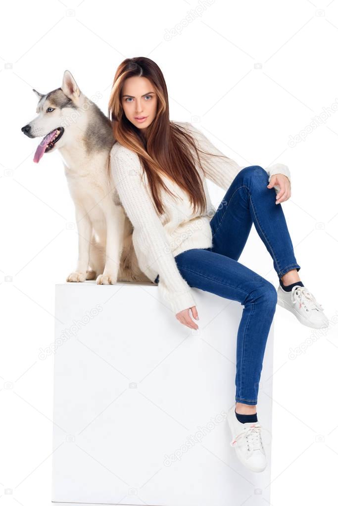 beautiful girl sitting on white cube with husky dog, isolated on white