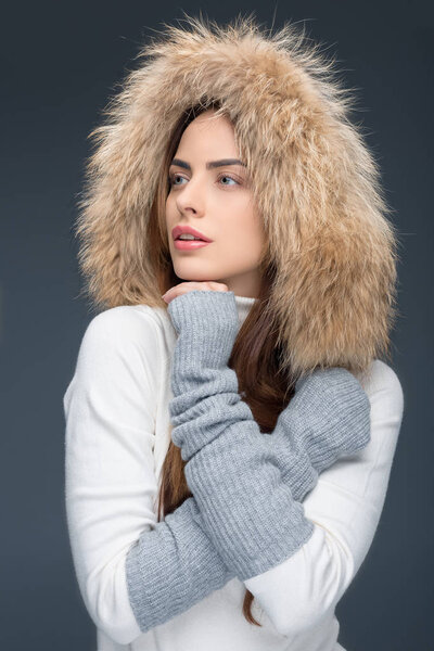 beautiful woman in fur hat and winter outfit, isolated on grey