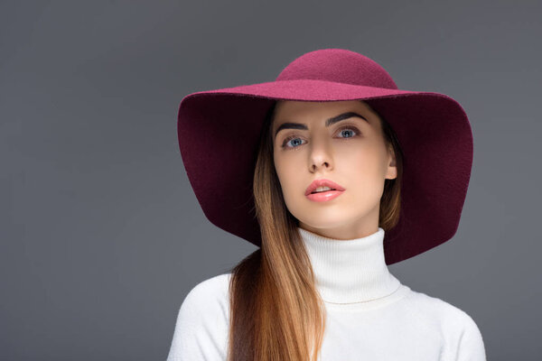 beauty posing in burgundy felt hat, isolated on grey
