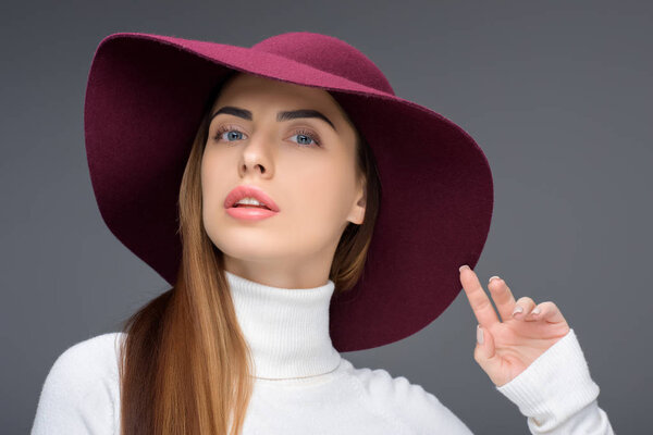 beautiful lady posing in burgundy felt hat, isolated on grey