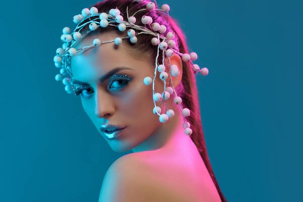 портрет красивой женщины с аксессуаром для волос, зимний макияж и блестки позируют для моды съемки, изолированные на синий
