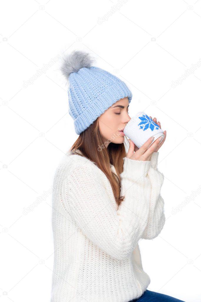 beautiful woman in knitted hat and winter sweater drinking coffee, isolated on white 