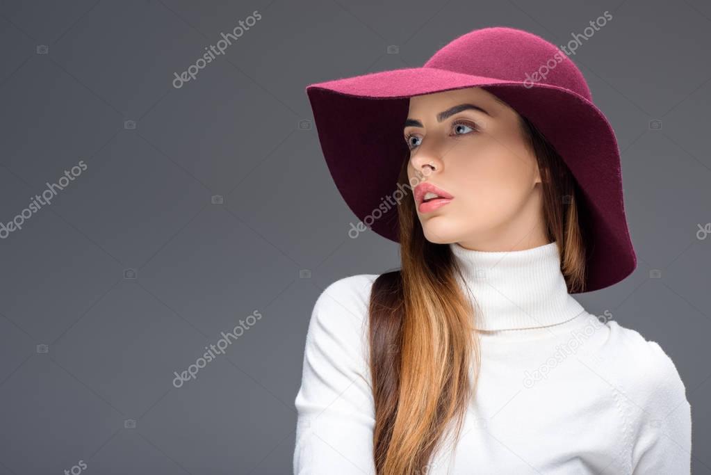 attractive woman posing in burgundy felt hat, isolated on grey