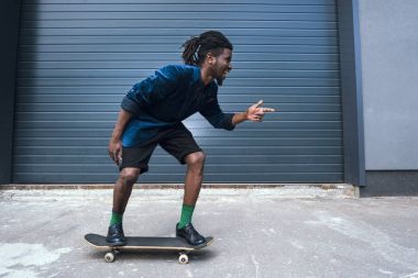 sokakta paten ve bir şeye işaret eden mavi ceketli şık Afro-Amerikan adamı
