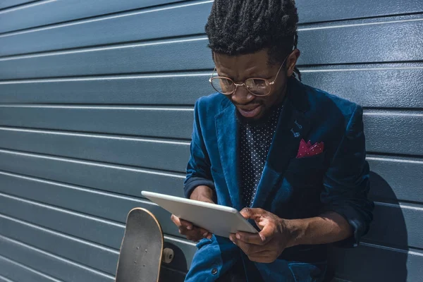 Homem americano africano elegante em casaco azul olhando para tablet — Fotografia de Stock