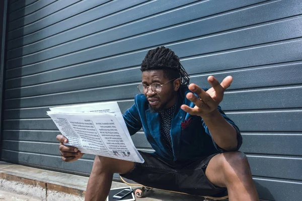 Chocado elegante homem americano africano em azul jaqueta ler jornal — Fotografia de Stock