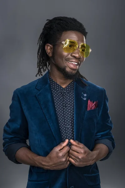 Smiling handsome african american man in yellow sunglasses looking away isolated on gray — Stock Photo, Image