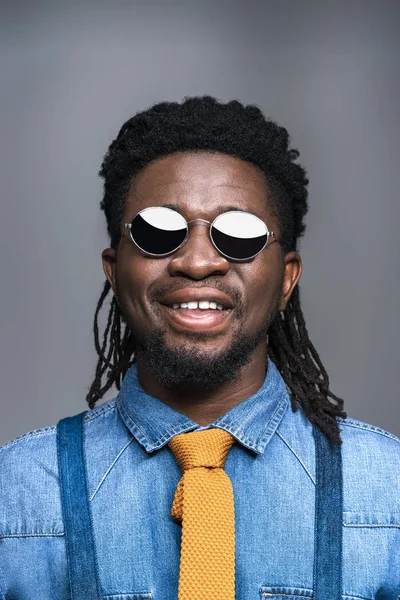 Smiling african american man in black sunglasses isolated on gray — Free Stock Photo