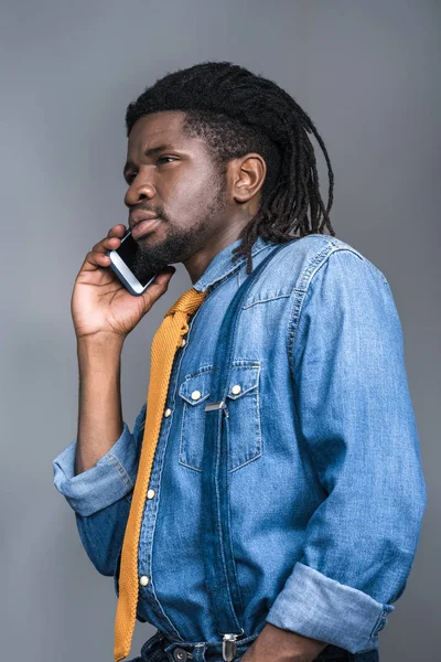 Κομψό σοβαρές αφρικανική αμερικανική άνθρωπος που μιλάει με smartphone που απομονώνονται σε γκρι — Δωρεάν Φωτογραφία