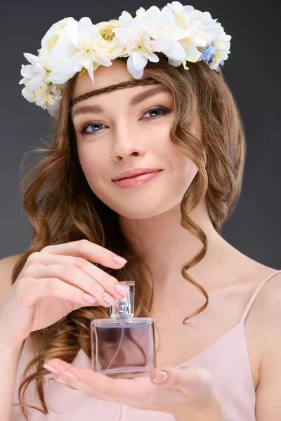 グレーに分離された香水のボトルを保持している巻き毛を持つ笑顔の女性 — ストック写真
